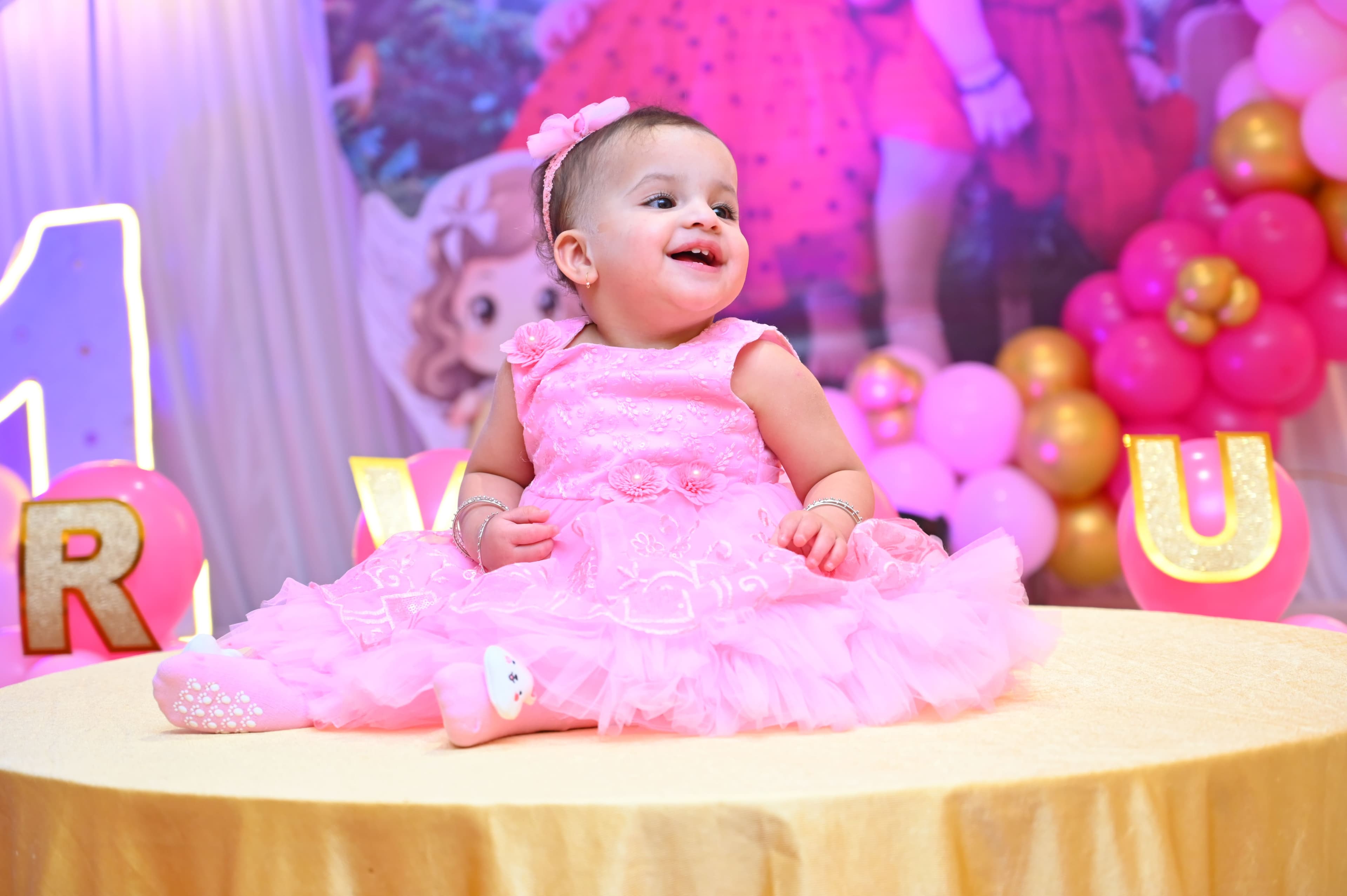 Baby girl in a pink tutu dress smiling at her first birthday
