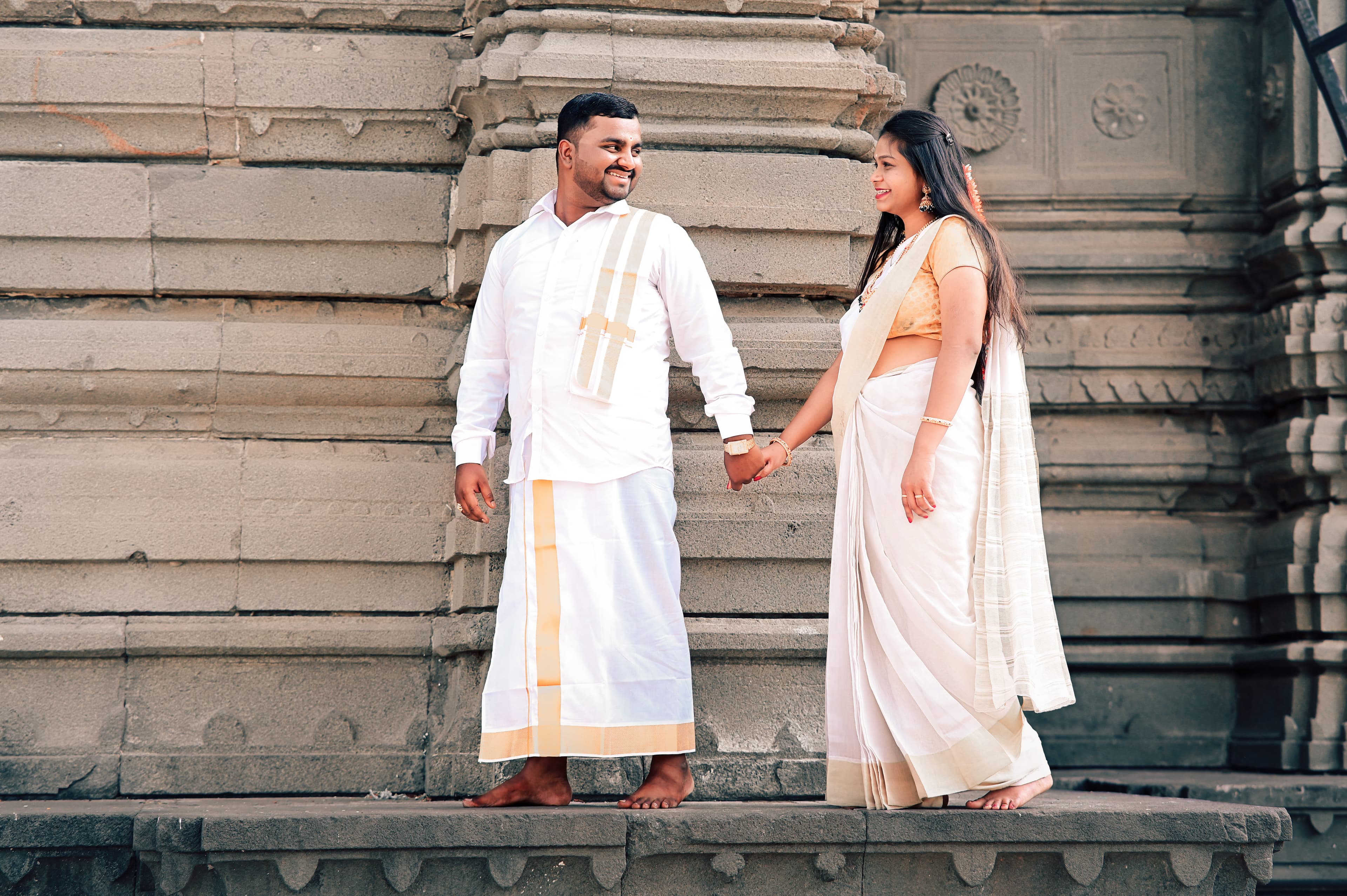 Couple holding hands against a carved stone temple wall