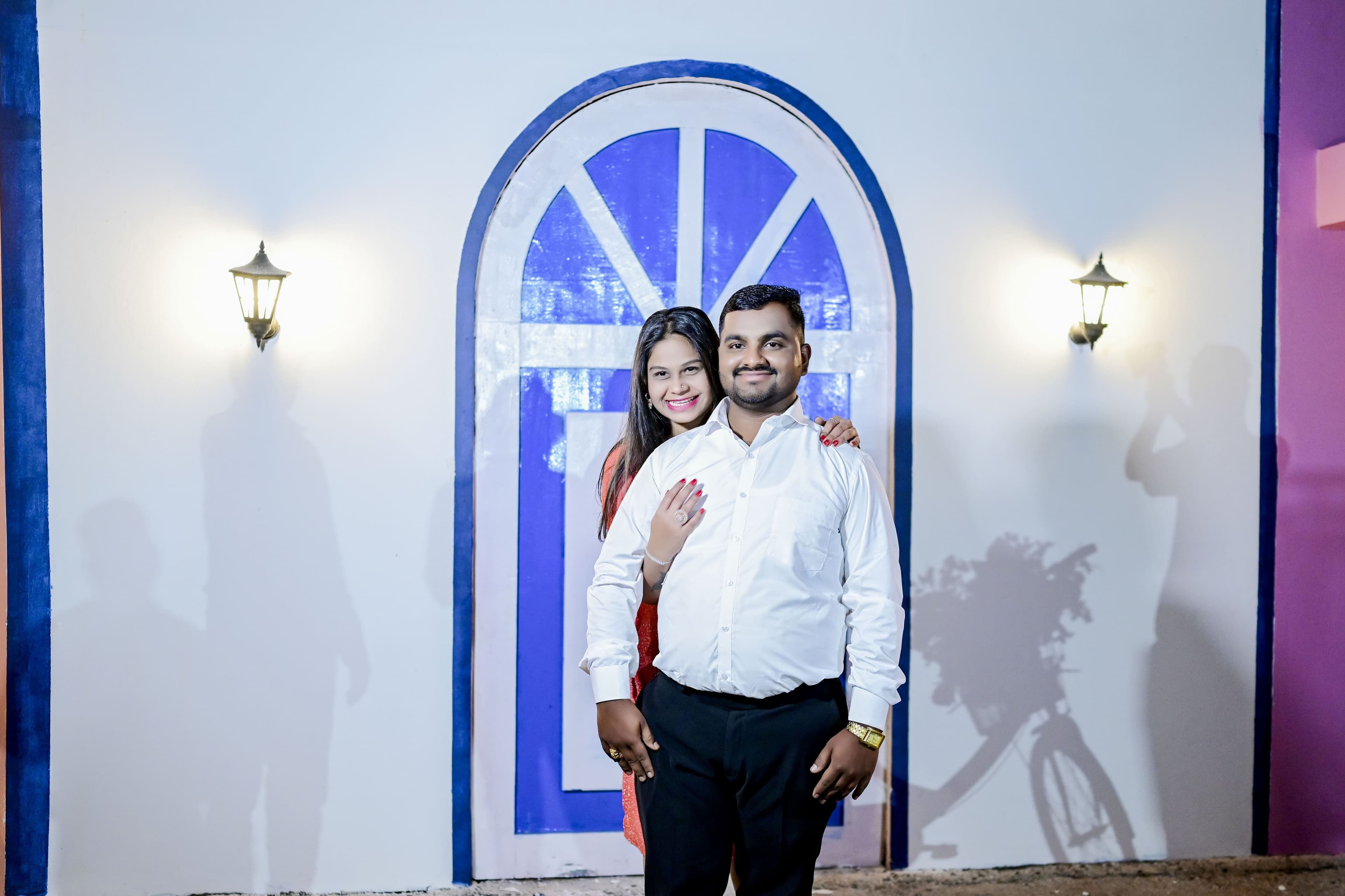Couple posing in front of a blue arched doorway
