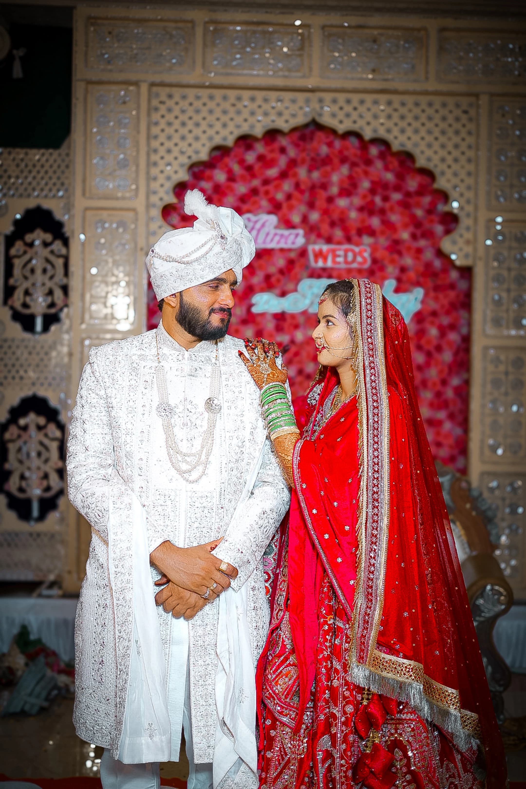 Bride and groom in front of a red rose wedding stage backdrop